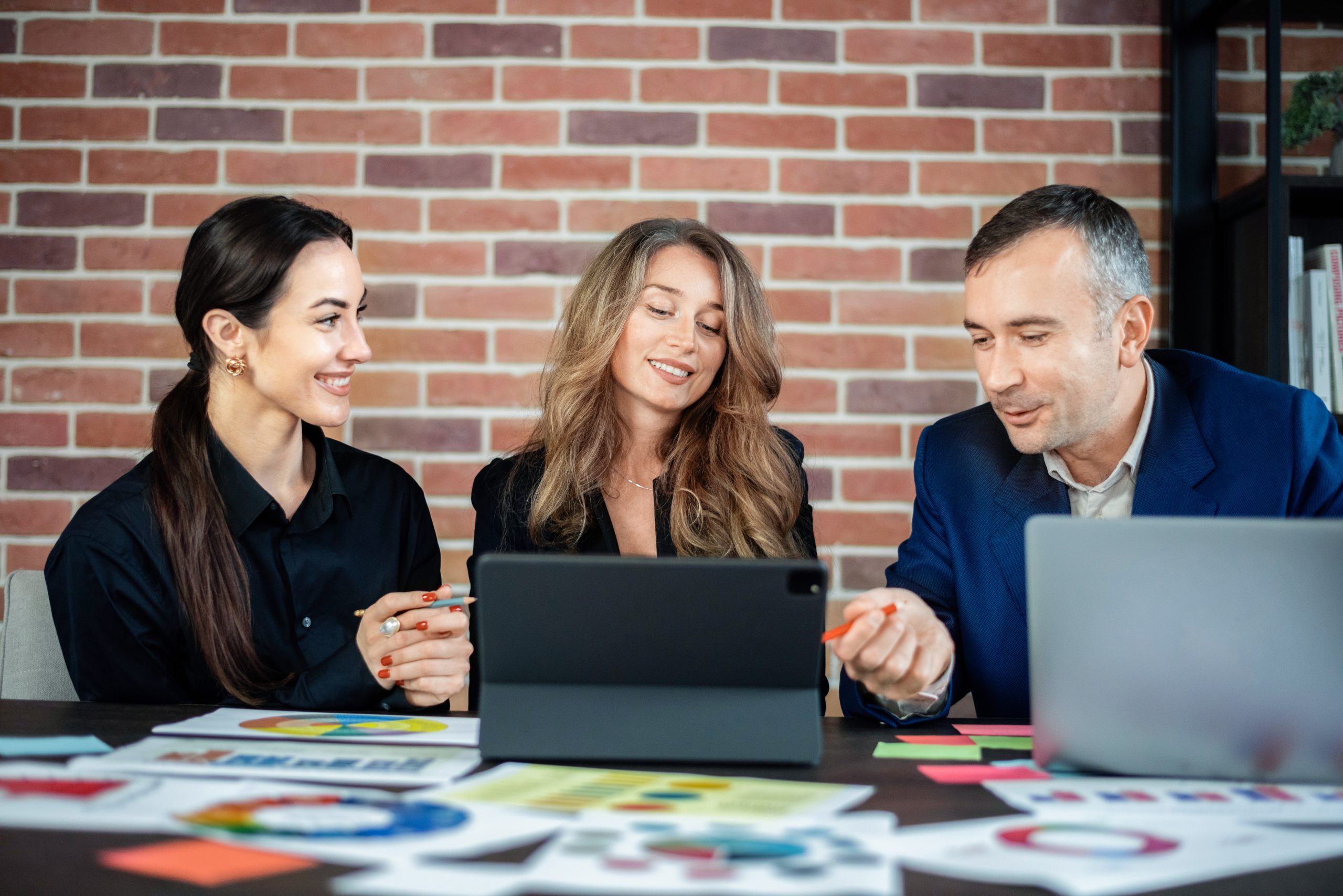 Business session in an office. Women and a man discussing business affairs. Gadgets and papers with graphs and notes